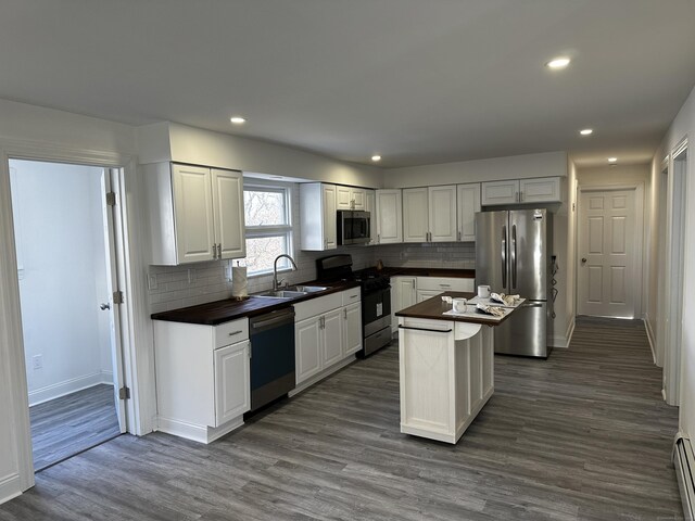 384 Sylvan Ave, Waterbury, CT 06706 - kitchen featuring stainless steel appliances, dark countertops, a sink, a baseboard radiator, and backsplash