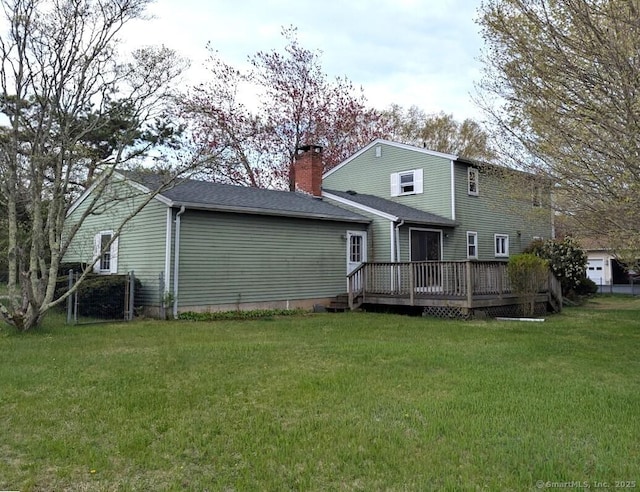 back of property featuring a lawn, a wooden deck, and a chimney