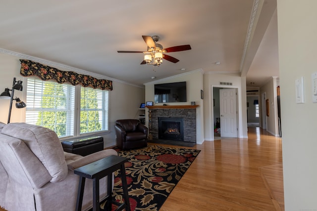 living room with ceiling fan, crown molding, a fireplace, wood finished floors, and baseboards