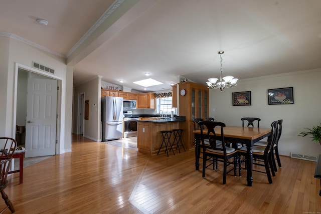 dining room with visible vents, light wood-style flooring, crown molding, and a notable chandelier