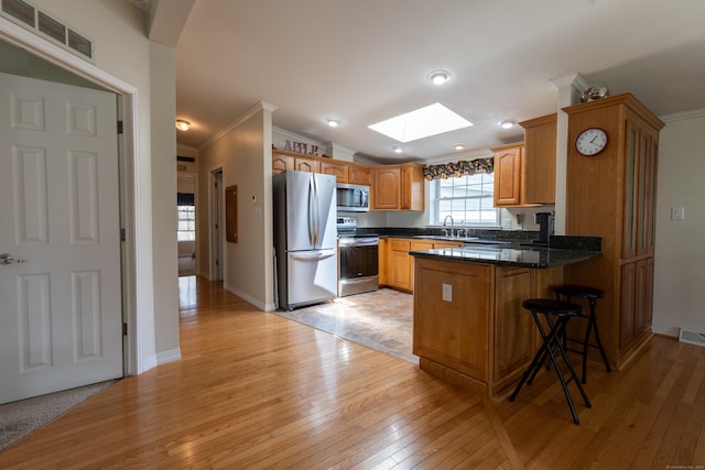 kitchen with visible vents, a skylight, appliances with stainless steel finishes, crown molding, and a peninsula