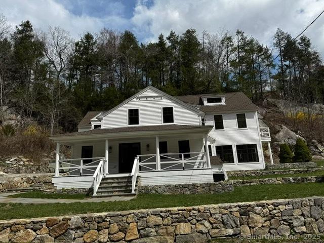 farmhouse featuring a porch and a front yard