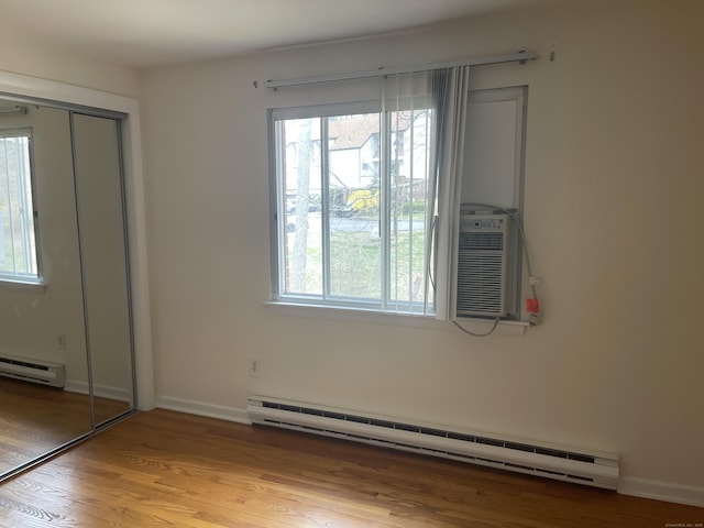 273 Queen St Apt 15E, Southington, CT 06489 - unfurnished bedroom featuring a baseboard heating unit, a closet, baseboards, light wood-style flooring, and baseboard heating