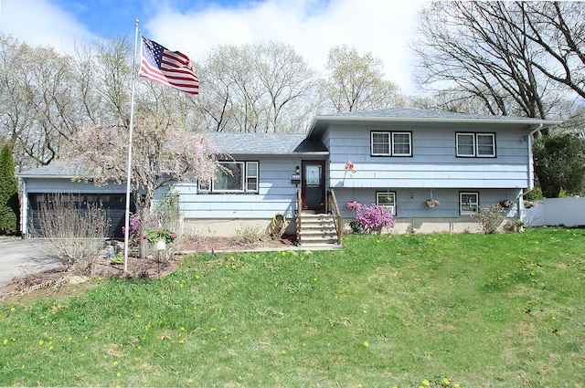 tri-level home featuring roof with shingles, a garage, a front yard, entry steps, and concrete driveway