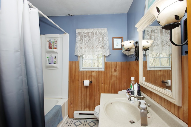 bathroom featuring wooden walls, wainscoting, a sink, baseboard heating, and shower / bath combo