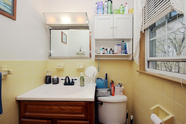 bathroom featuring toilet, tile walls, plenty of natural light, and vanity