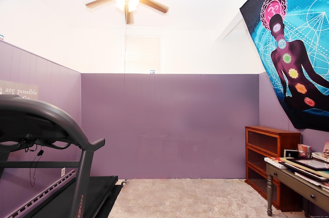 workout room with a ceiling fan, wood walls, and carpet