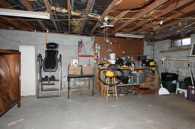 unfinished basement featuring concrete block wall and a workshop area