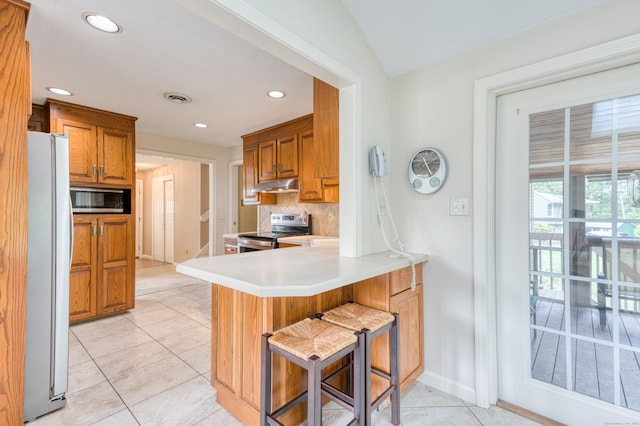 18 Black Birch Rd, Plainville, CT 06062 - kitchen with stainless steel appliances, under cabinet range hood, light tile patterned floors, a peninsula, and backsplash