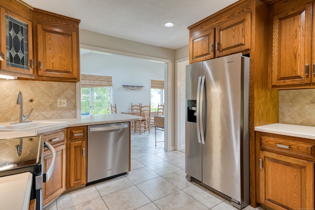 18 Black Birch Rd, Plainville, CT 06062 - kitchen featuring appliances with stainless steel finishes, brown cabinetry, light tile patterned floors, decorative backsplash, and recessed lighting