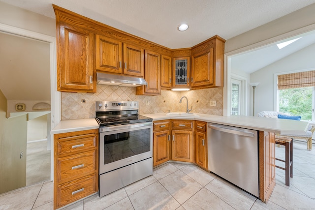18 Black Birch Rd, Plainville, CT 06062 - kitchen featuring appliances with stainless steel finishes, under cabinet range hood, tasteful backsplash, brown cabinets, and vaulted ceiling