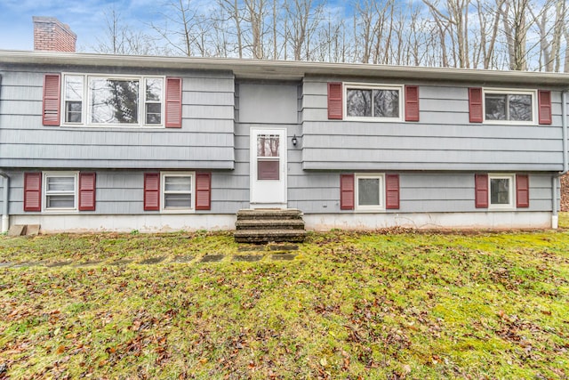 bi-level home featuring a front yard, entry steps, and a chimney