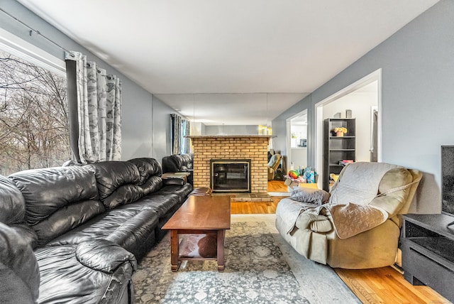 living area featuring wood finished floors and a brick fireplace
