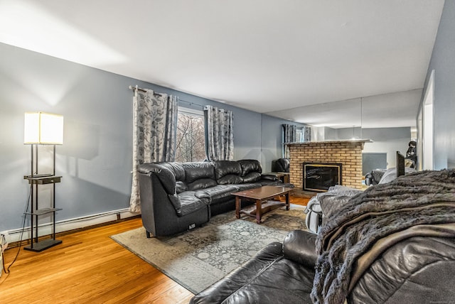 living area with baseboard heating, baseboards, a brick fireplace, and wood finished floors