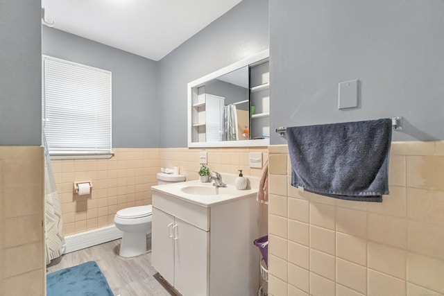 full bathroom featuring toilet, tile walls, wainscoting, wood finished floors, and vanity