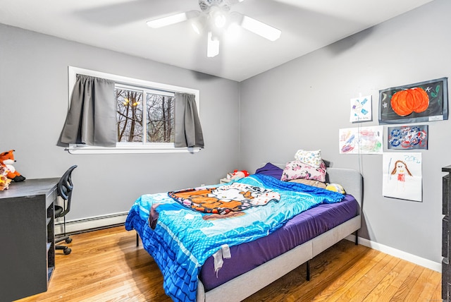 bedroom with a baseboard heating unit, wood finished floors, and ceiling fan