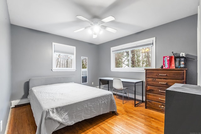 bedroom with a baseboard heating unit, a baseboard radiator, a ceiling fan, and hardwood / wood-style flooring