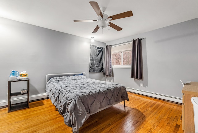 bedroom featuring a baseboard heating unit, hardwood / wood-style floors, a ceiling fan, and baseboard heating
