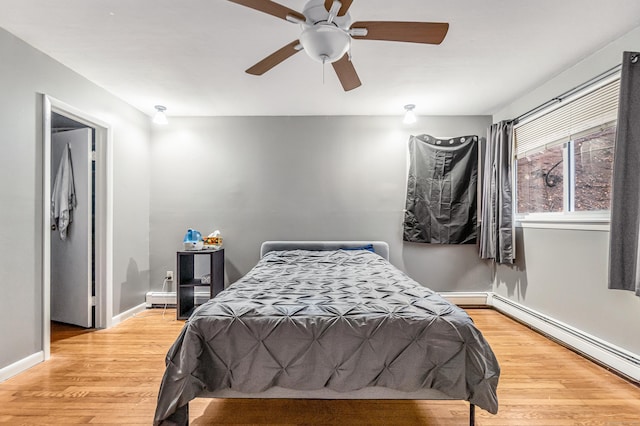 bedroom featuring baseboards, wood finished floors, a baseboard radiator, and baseboard heating