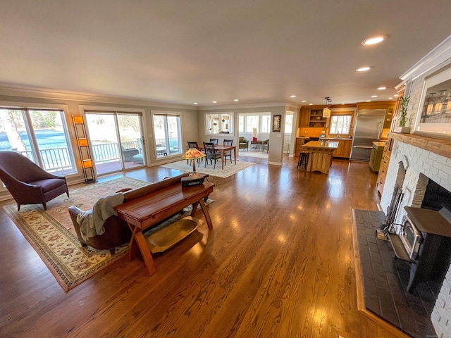 living area featuring recessed lighting, dark wood-style floors, ornamental molding, and a wood stove