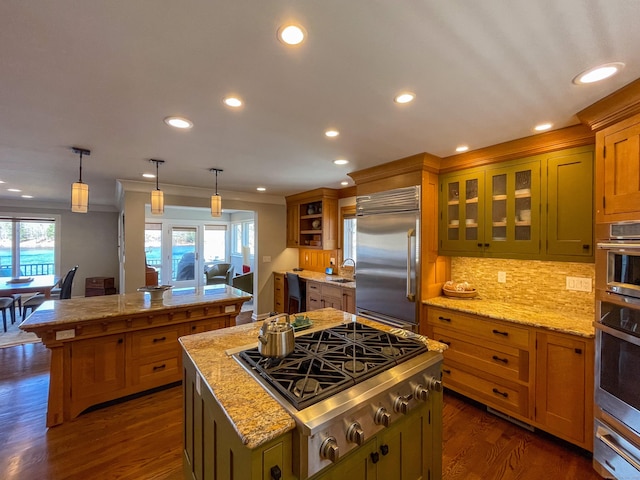 kitchen featuring appliances with stainless steel finishes, a center island, a warming drawer, decorative backsplash, and a sink