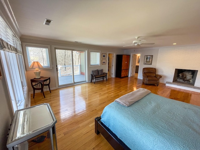 bedroom with crown molding, visible vents, access to exterior, and a brick fireplace