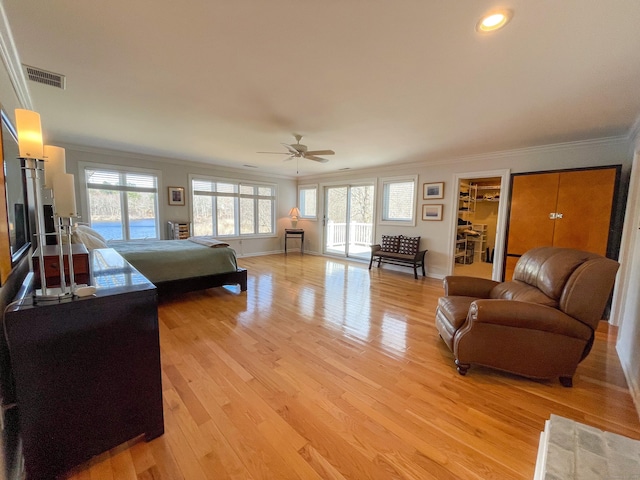 living area featuring a ceiling fan, light wood finished floors, ornamental molding, and visible vents