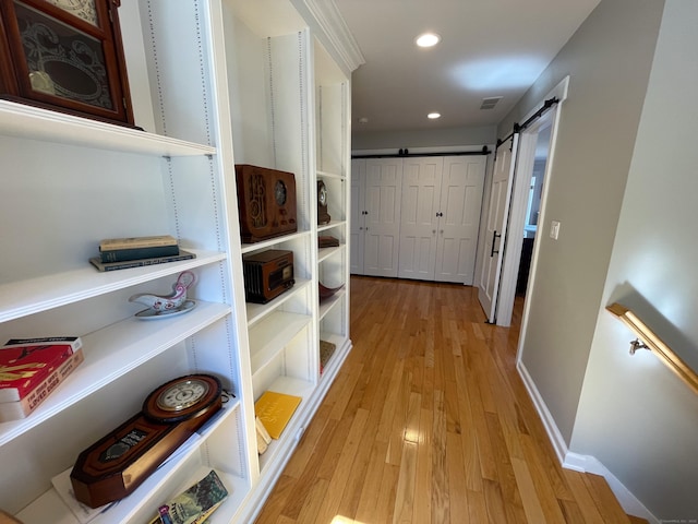 hall featuring baseboards, recessed lighting, light wood-style flooring, a barn door, and visible vents