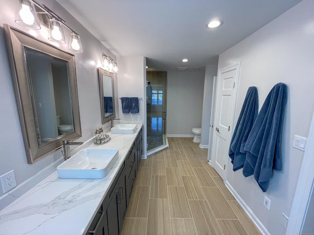bathroom featuring recessed lighting, a stall shower, a sink, and toilet