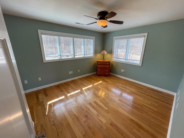 empty room featuring visible vents, baseboards, light wood finished floors, and a ceiling fan