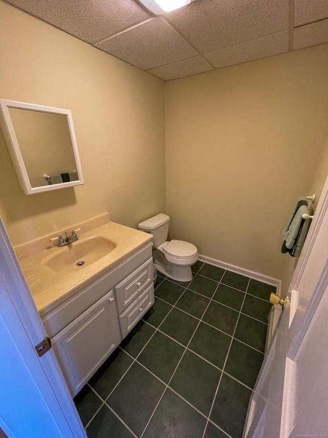 half bathroom with tile patterned floors, vanity, a paneled ceiling, and toilet