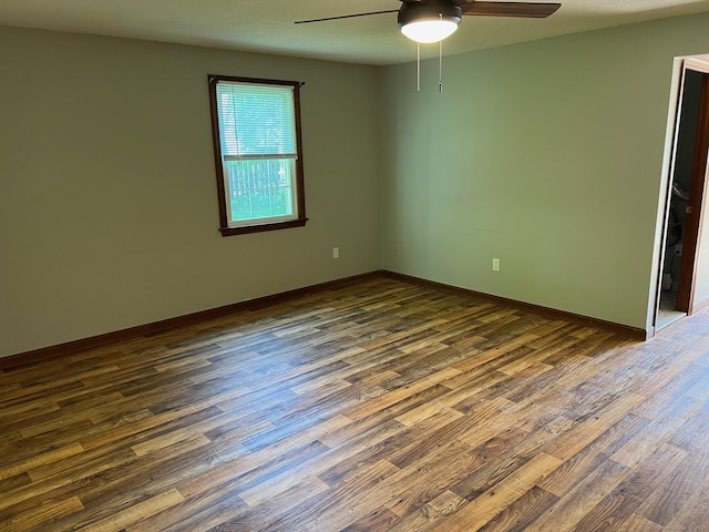 unfurnished room with ceiling fan, dark wood-style floors, and baseboards