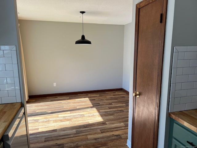 unfurnished dining area with dark wood-style floors and baseboards