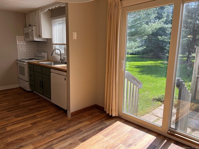 kitchen featuring white appliances, a sink, backsplash, dark wood-type flooring, and healthy amount of natural light