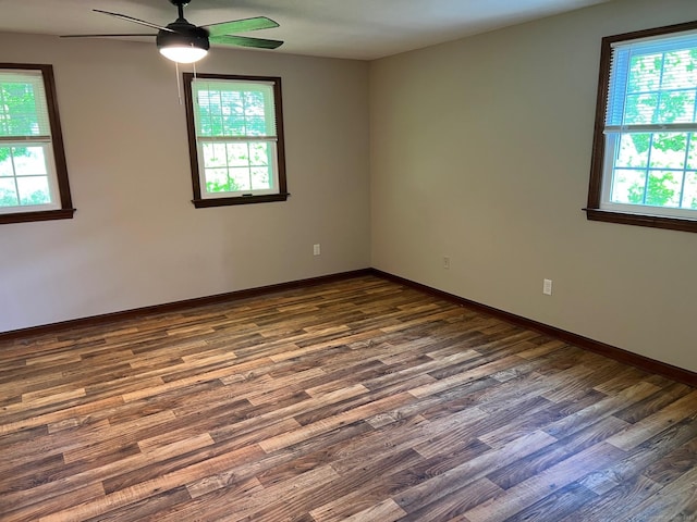 unfurnished room featuring healthy amount of natural light, ceiling fan, and dark wood-style flooring