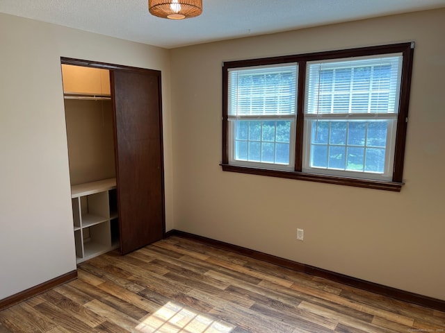 unfurnished bedroom featuring a closet, baseboards, and dark wood-type flooring