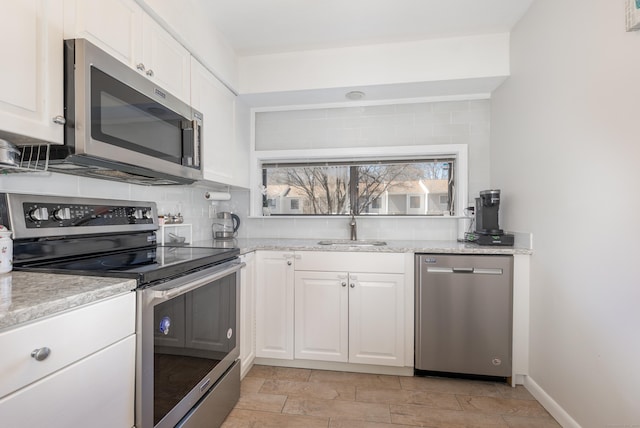 kitchen featuring appliances with stainless steel finishes, decorative backsplash, a sink, and white cabinetry