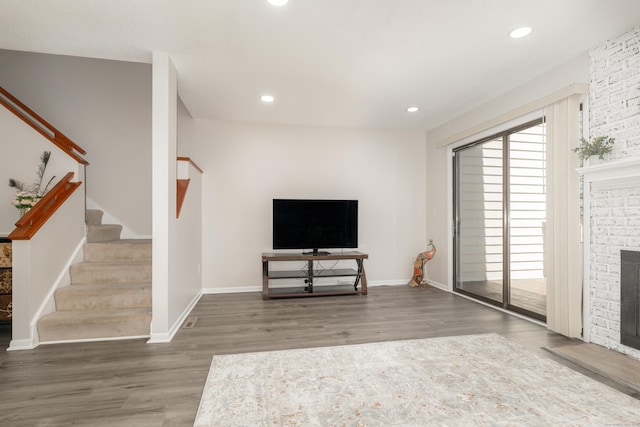 unfurnished living room featuring wood finished floors, recessed lighting, a fireplace, and stairs