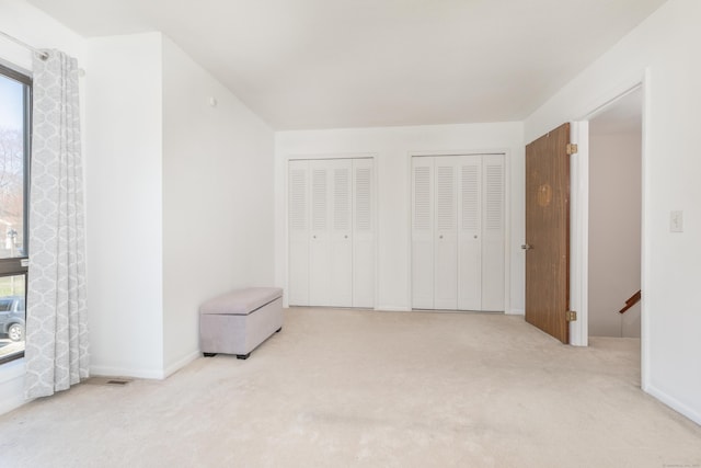 unfurnished bedroom featuring carpet flooring, baseboards, and multiple closets