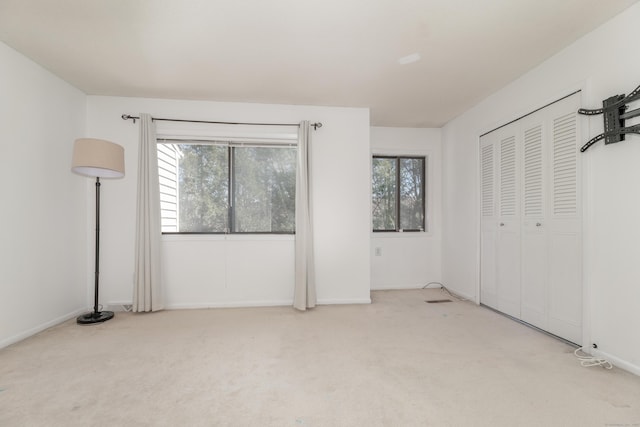 unfurnished bedroom with a closet, baseboards, multiple windows, and carpet flooring