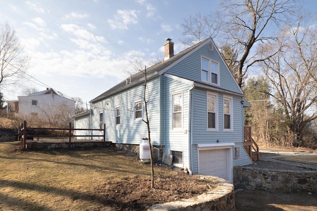 view of side of property with a wooden deck, a lawn, a garage, and a chimney