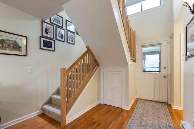 stairway with wood finished floors, baseboards, and a healthy amount of sunlight