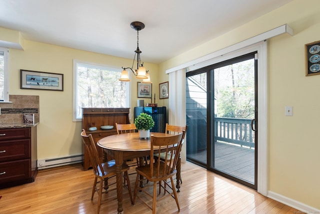 dining room featuring baseboard heating, light wood-type flooring, and baseboards
