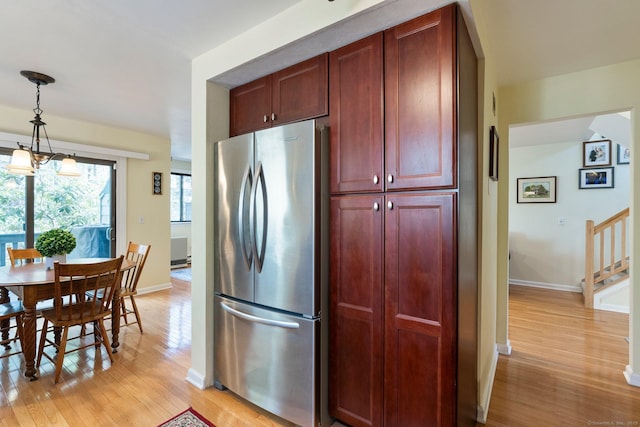 kitchen with baseboards, freestanding refrigerator, reddish brown cabinets, pendant lighting, and light wood-style flooring