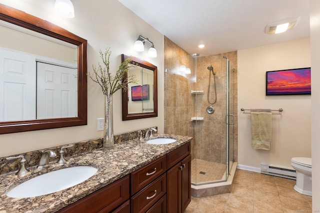 bathroom with a shower stall, a baseboard heating unit, a sink, and toilet