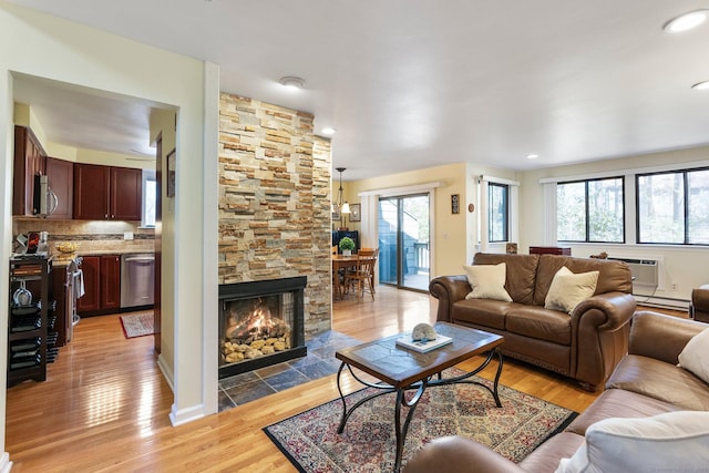 living room featuring baseboard heating, light wood-style floors, a wall unit AC, and recessed lighting