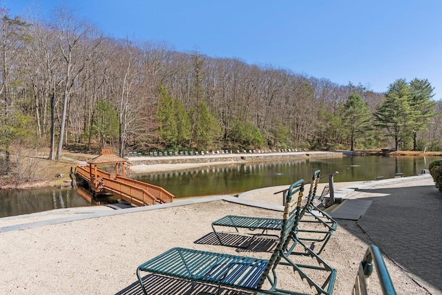 view of dock with a forest view and a water view