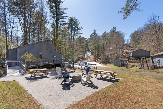 view of patio featuring a deck, an outbuilding, and a fire pit