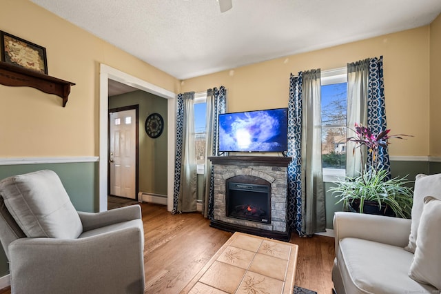 61 Harrington St, Meriden, CT 06451 - living area with a stone fireplace, a baseboard heating unit, and wood finished floors