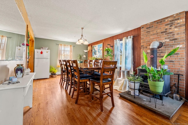 61 Harrington St, Meriden, CT 06451 - dining room featuring a wood stove, a notable chandelier, a textured ceiling, and light wood-style flooring